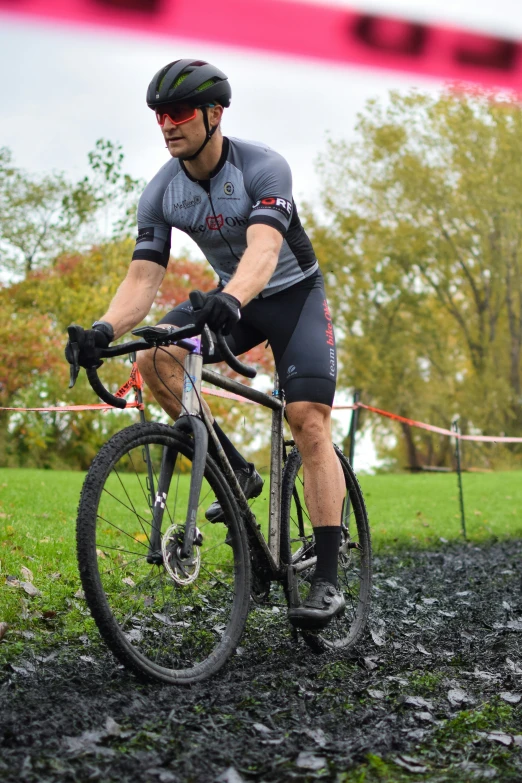 a cyclist in gray gear riding on the mud