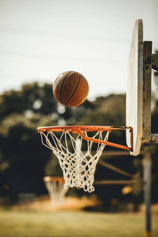 a basketball going up into the basket in an outdoor gym