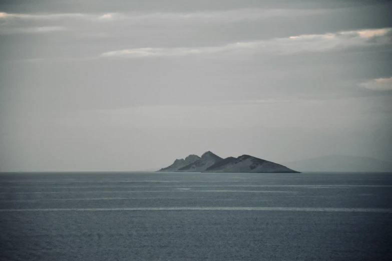 three rocks on top of an island surrounded by the ocean