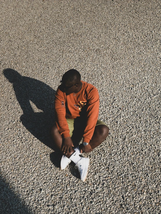 man sits on ground looking down in depression