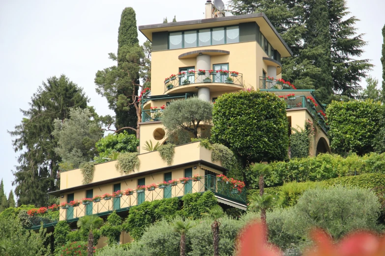 a multi - story house with lots of plants and flowers on its side