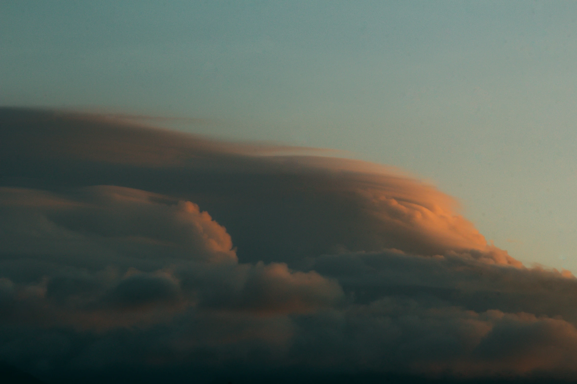 large cloud above the ground with a plane in the sky