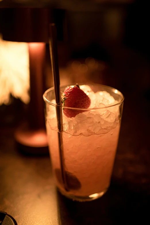 a glass on a table filled with ice and strawberries