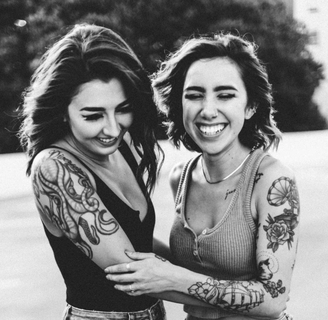 two women with tattoos posing for a black and white po
