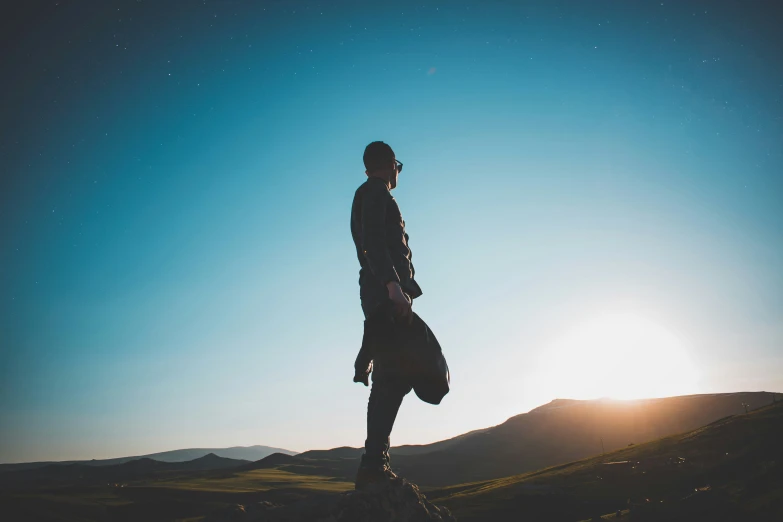 a person standing on top of a rock in the sunset