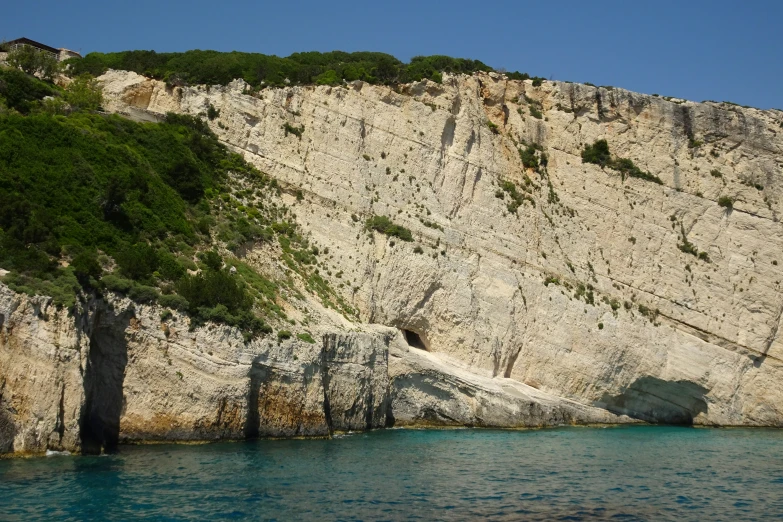 a rocky cliff by the water, with some trees growing on top