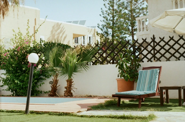 a chair and table with a lamp near a pool