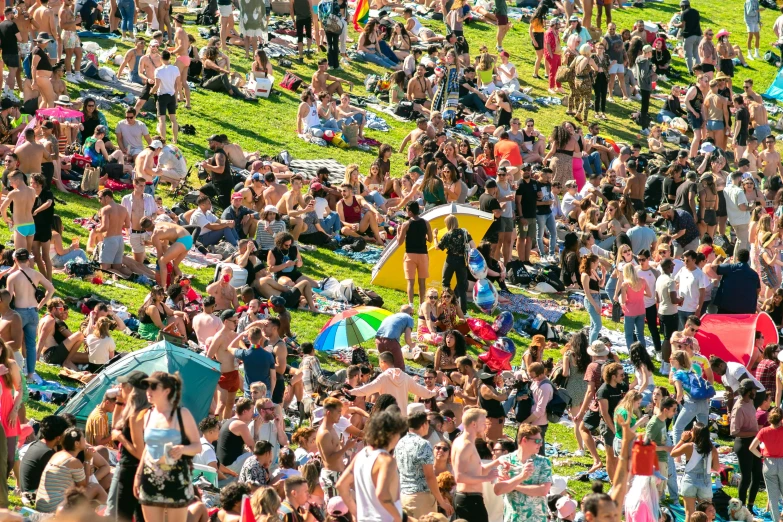 a crowd of people on the grass next to umbrellas