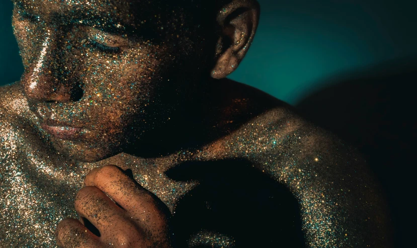 a male in a glittery gold dress looking intently at soing