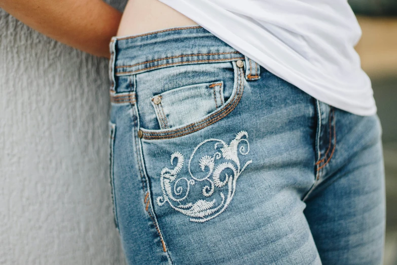 closeup of the belly of a  with her hands in the pocket of an jean - style pants