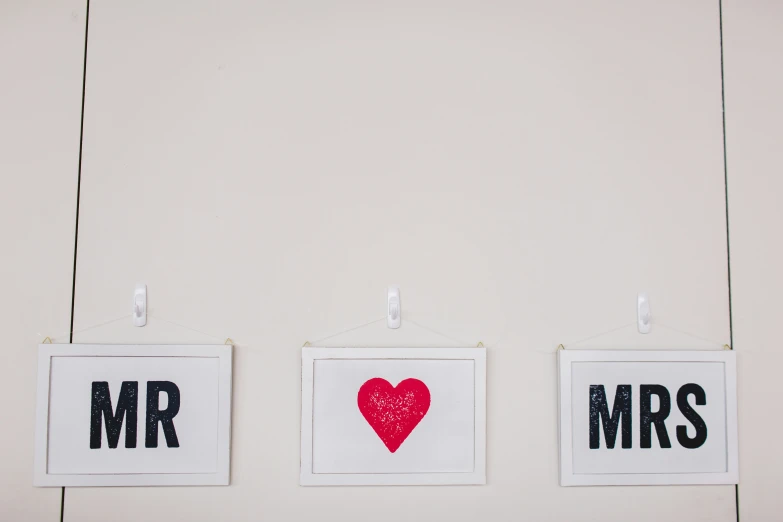 two pictures of a red heart hanging from hooks