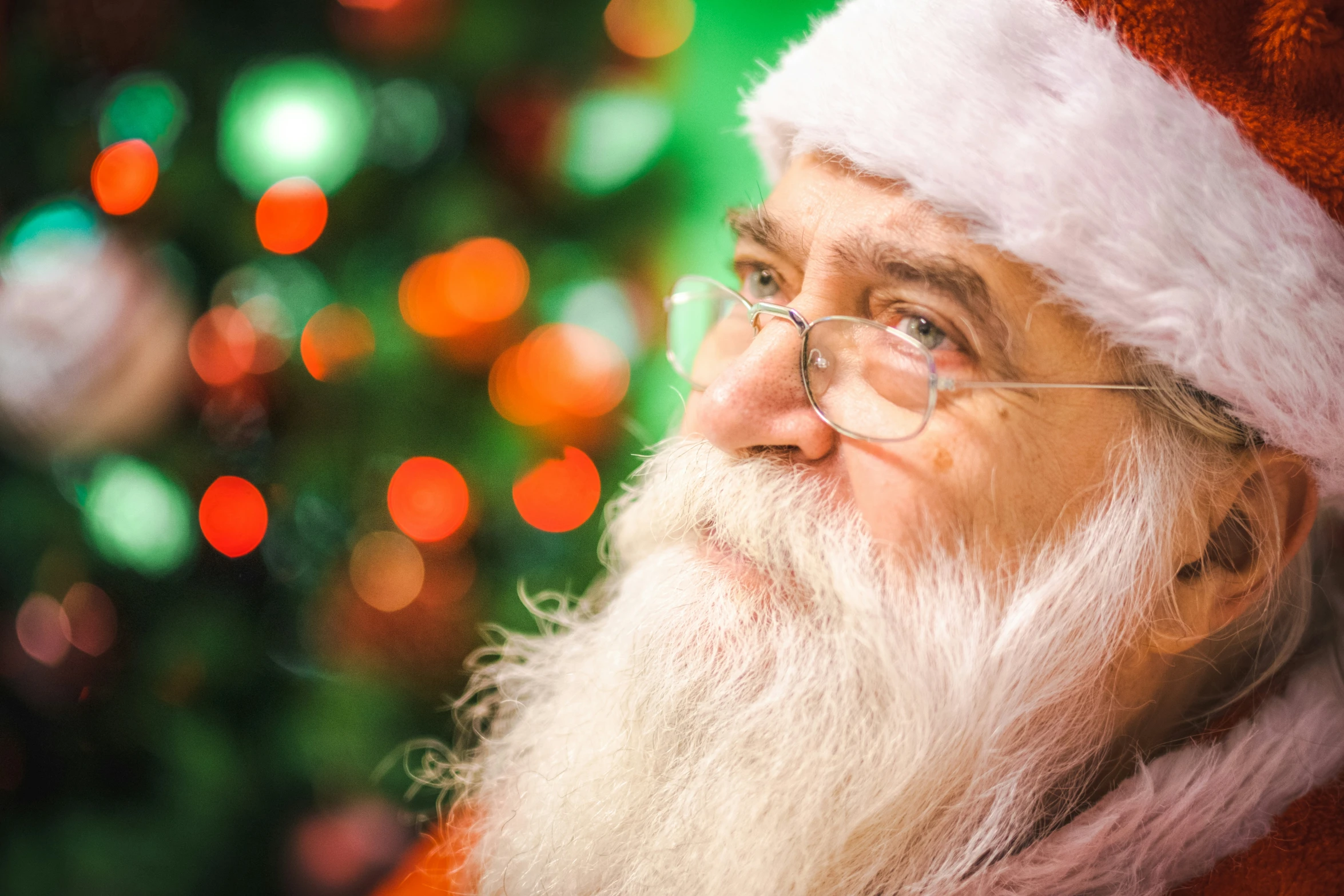 a man wearing a santa claus hat in front of a tree