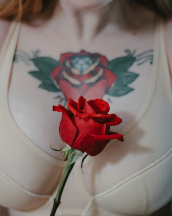 a rose with tattoo on it sitting in front of a woman