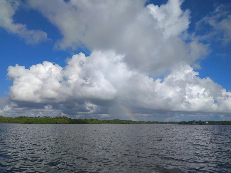 clouds float by a boat on a body of water