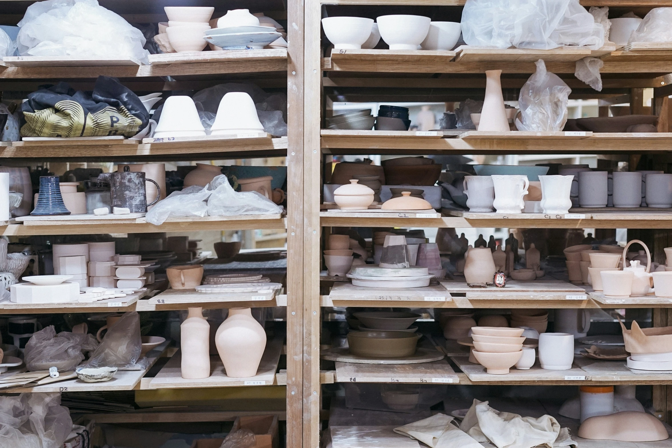 the shelves of a pottery shop are filled with different colors