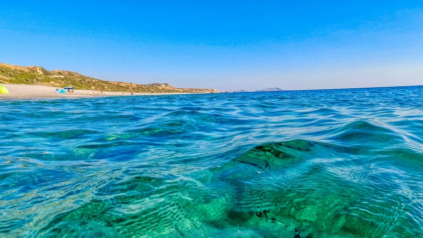 some clear blue water and mountains in the distance