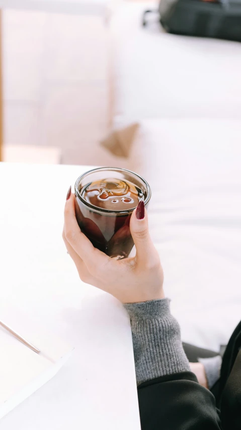 a woman holding a soda drink at a table