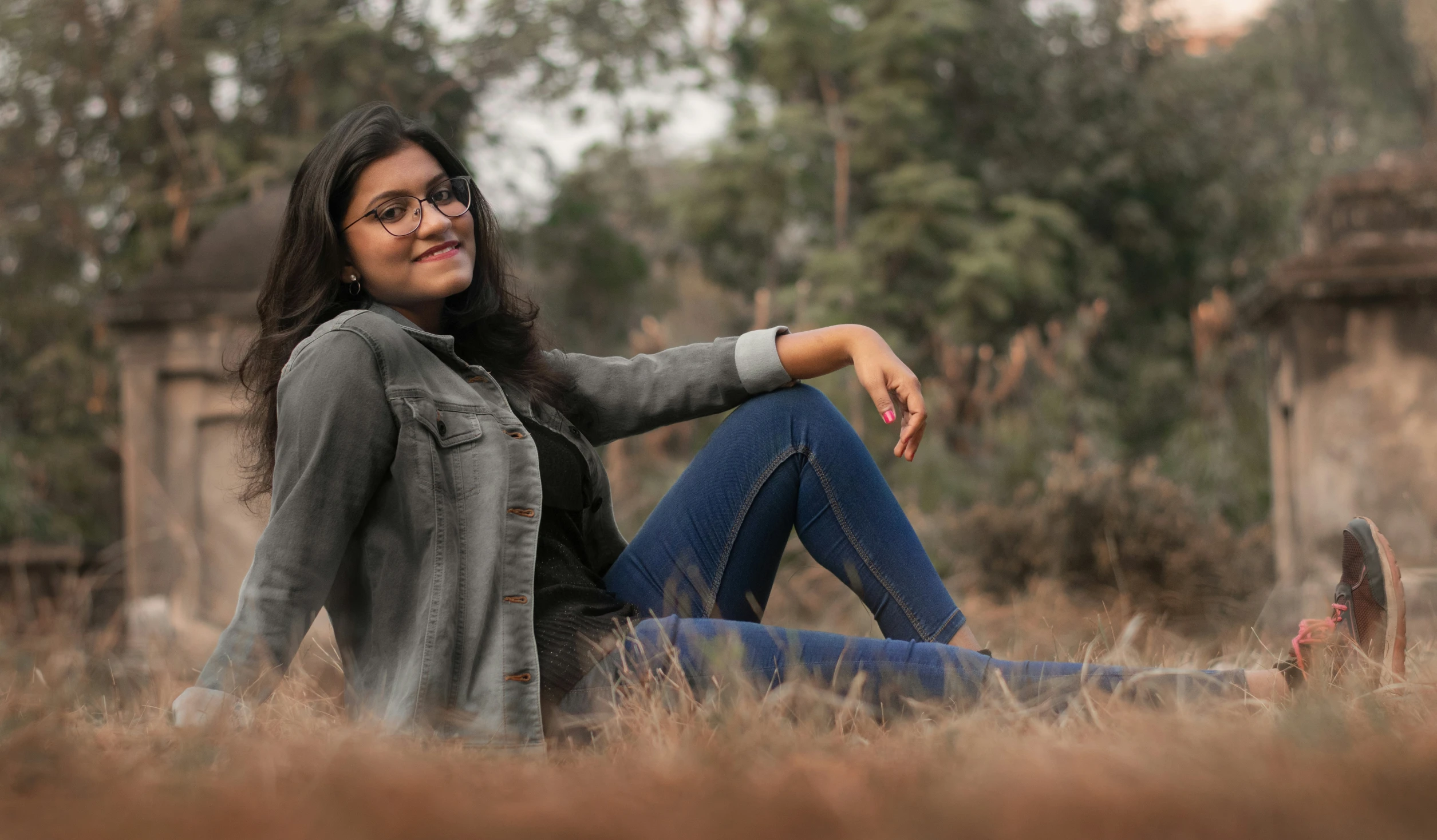 an indian woman sitting on the ground in the grass smiling