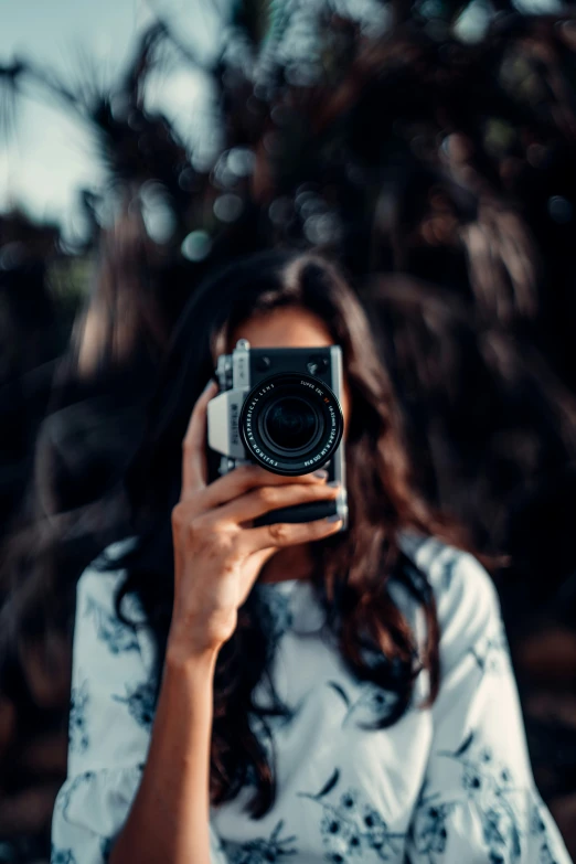 a woman holding a camera looking into the mirror