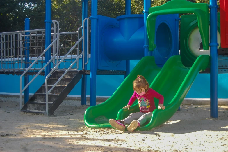 a child sitting in front of a green slide