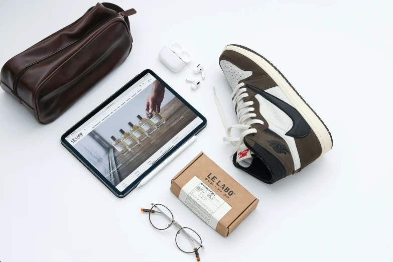 a pair of sneakers, glasses, and other items from a shoe collection are laid out