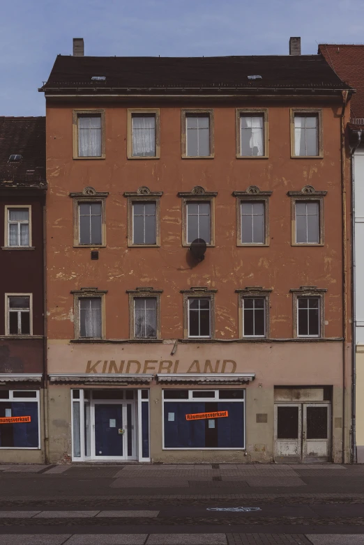 an old run down brown building with shutters opened and a few windows