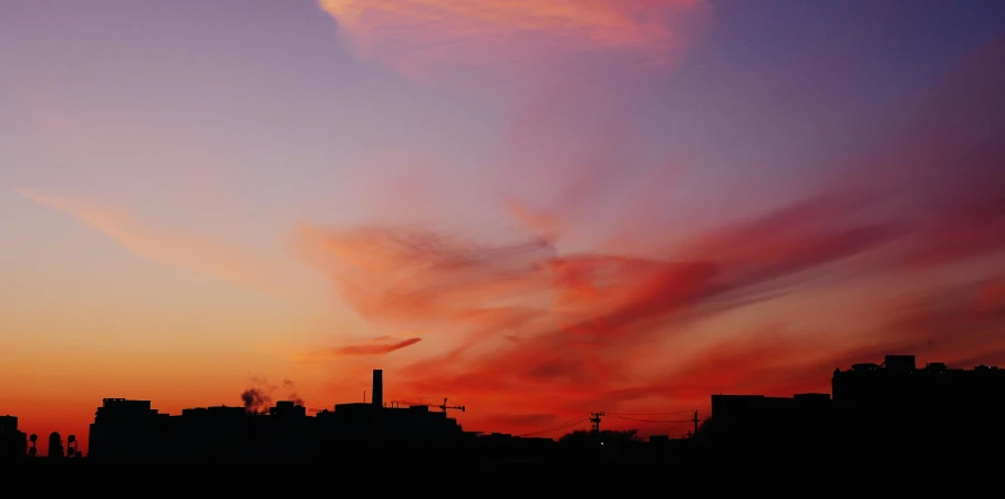 colorful clouds float over an urban skyline