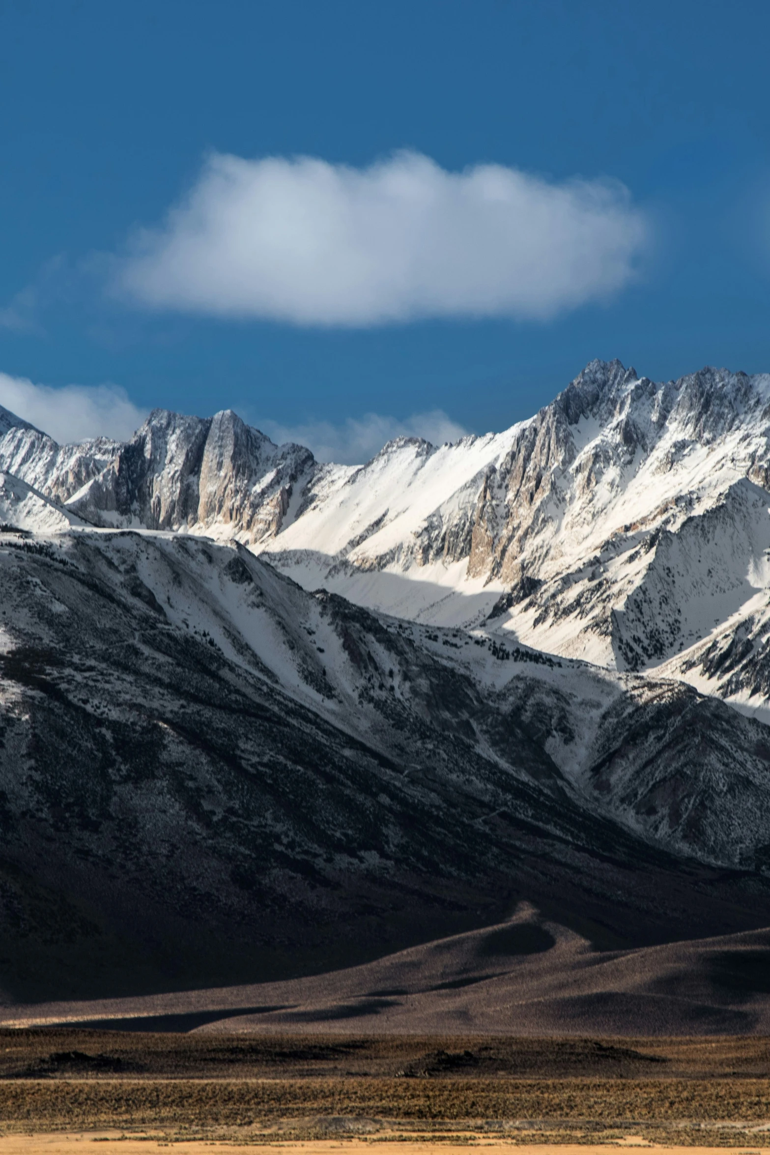 a mountain range with a few clouds in the sky