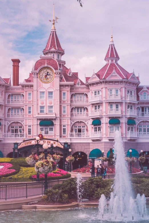 a big pink building is next to some fountains