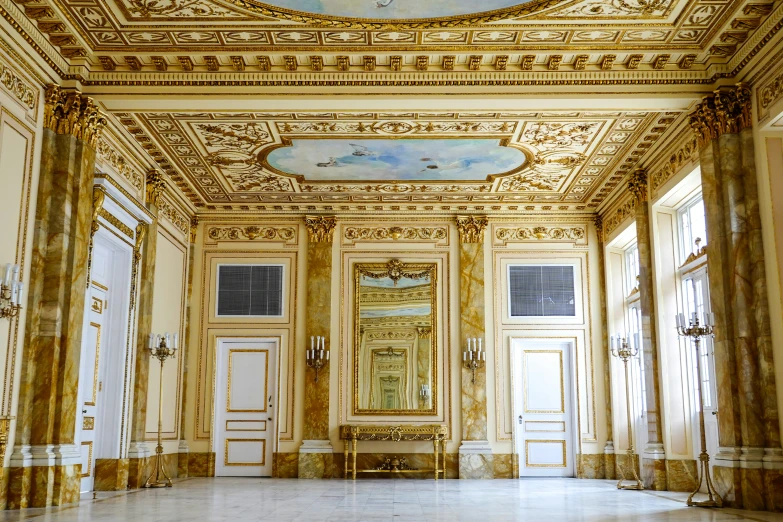 a room with gold and white painted ceiling and several doors