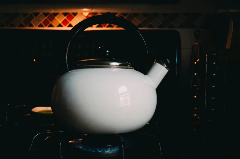 a white tea pot sitting on top of an oven