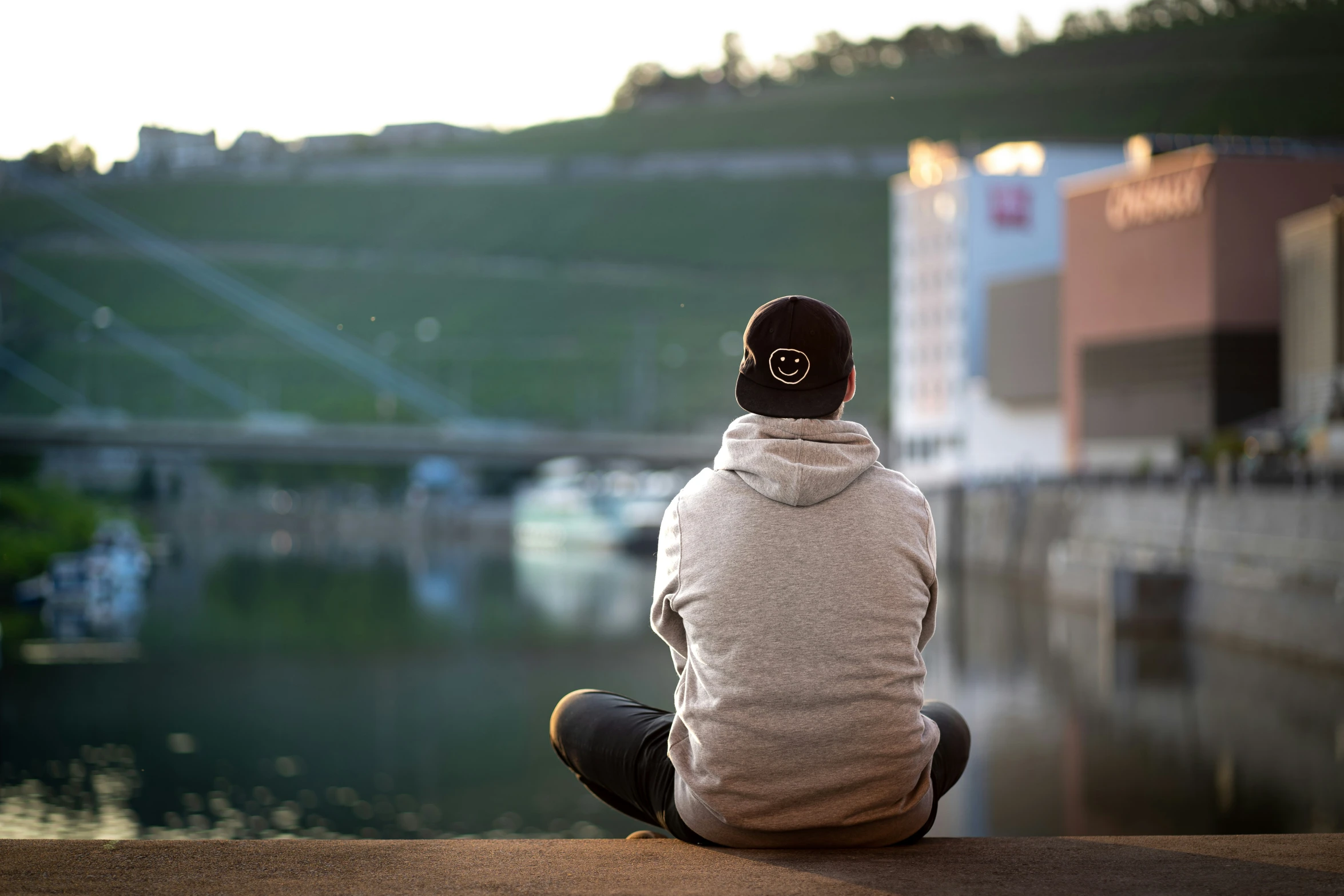 a person sitting on the ground looking out at the river