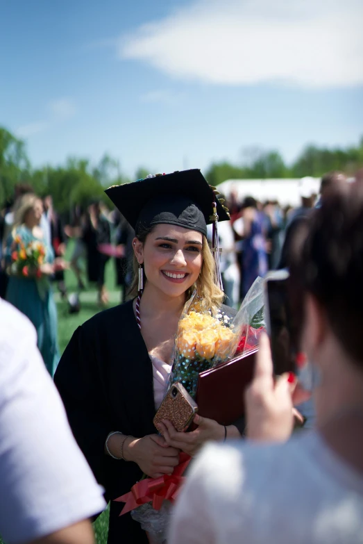 a graduate holding flowers and a book smiles for the camera