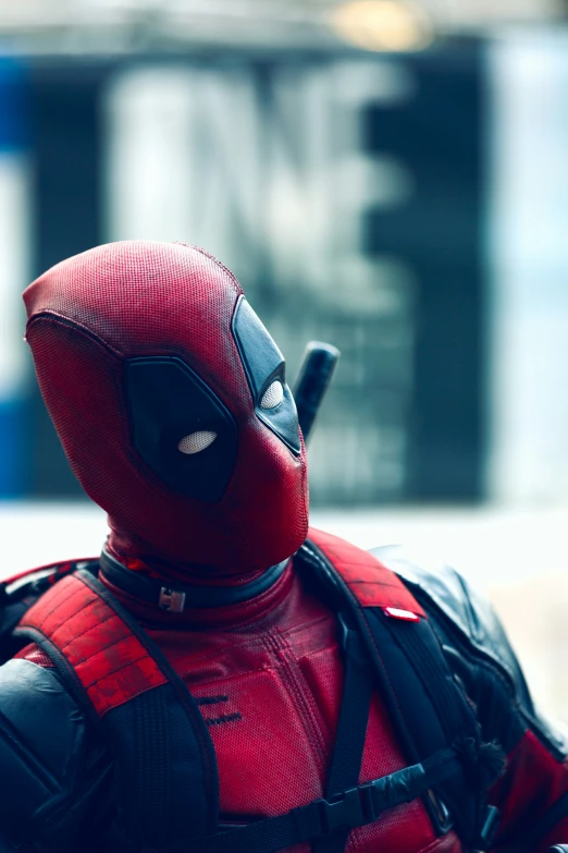 a deadpool man wearing a red mask and carrying a bag