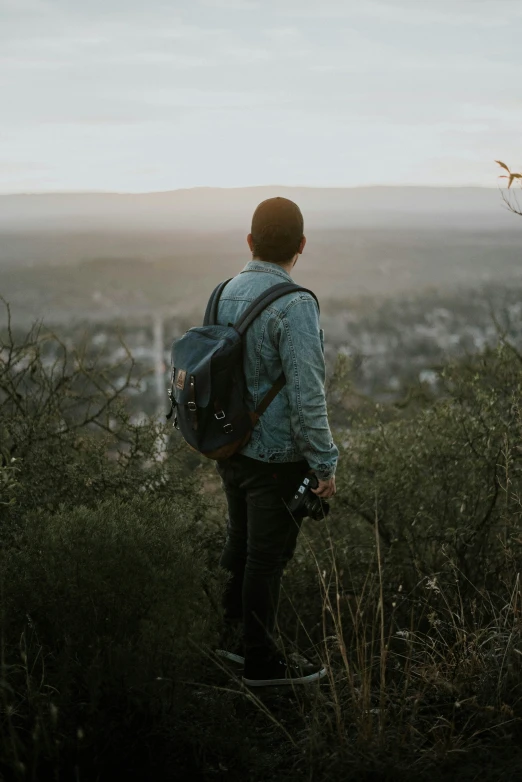 man with blue backpack standing alone over a city