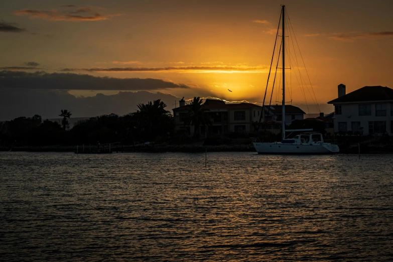 the sun sets over a large building over water