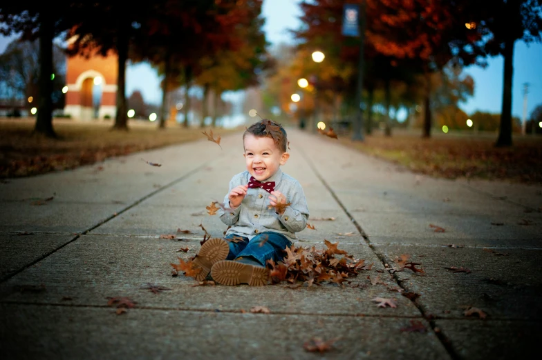 a little boy sitting down and playing with leaves