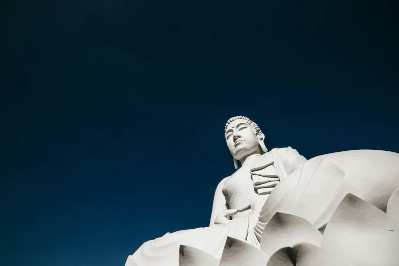 a statue sitting in front of a blue sky