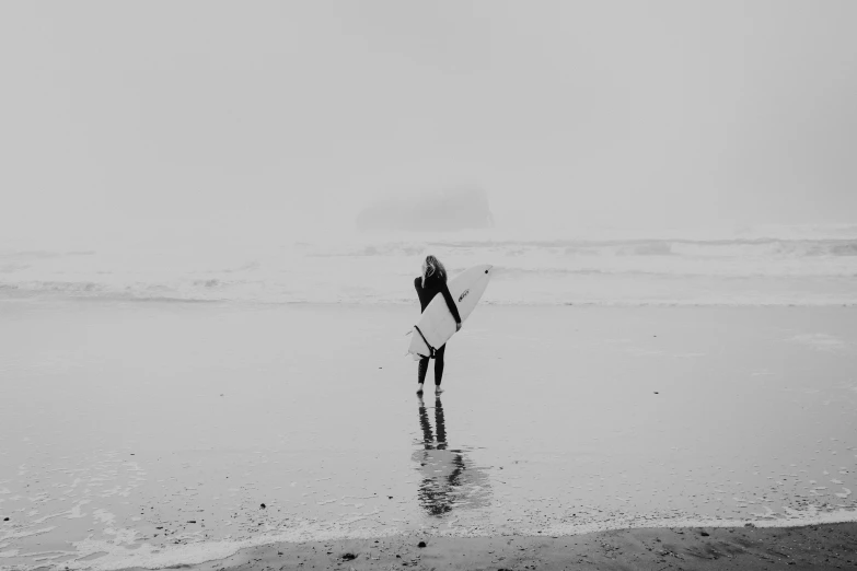 a person carrying a surfboard along the beach