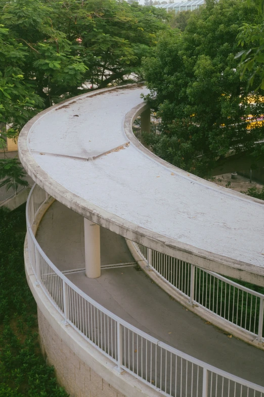 the curved concrete walkway has a railing at the top