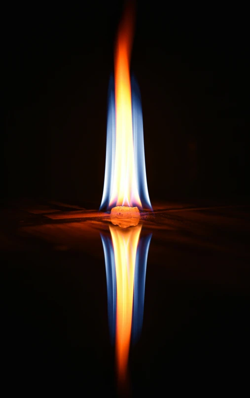 a single fire burning in the dark with a reflection on the water