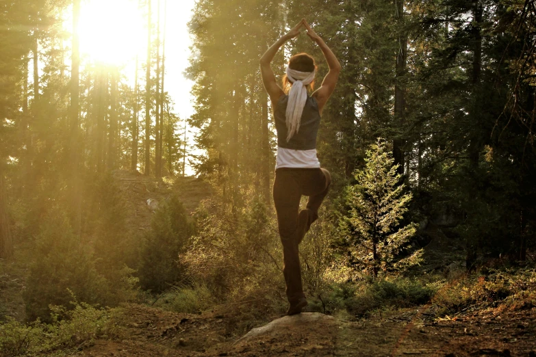 a woman doing yoga outdoors in the middle of the forest