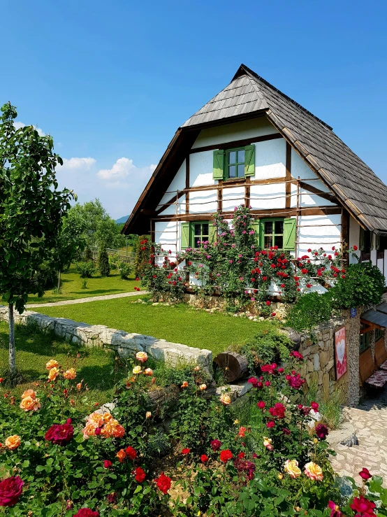 an old white cottage sits among lush flowers