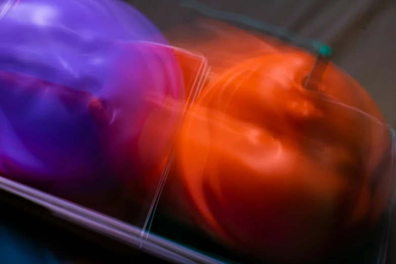 two plastic bowls with an orange and purple ball in them