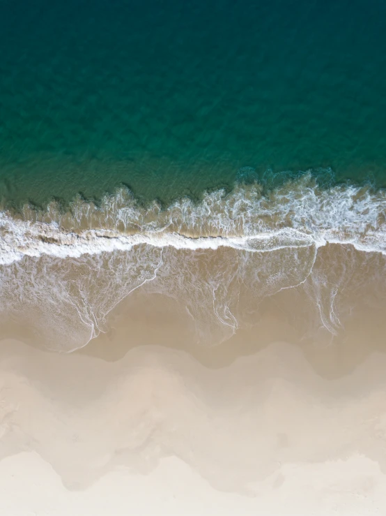 an aerial view of the ocean and sand