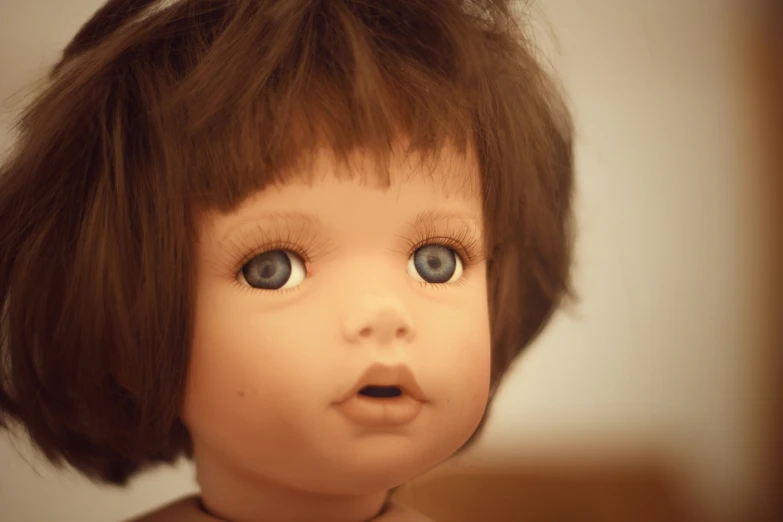 an doll with large blue eyes stares off into the distance