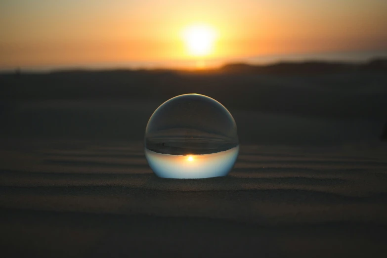a glass sphere sitting on top of a sandy beach