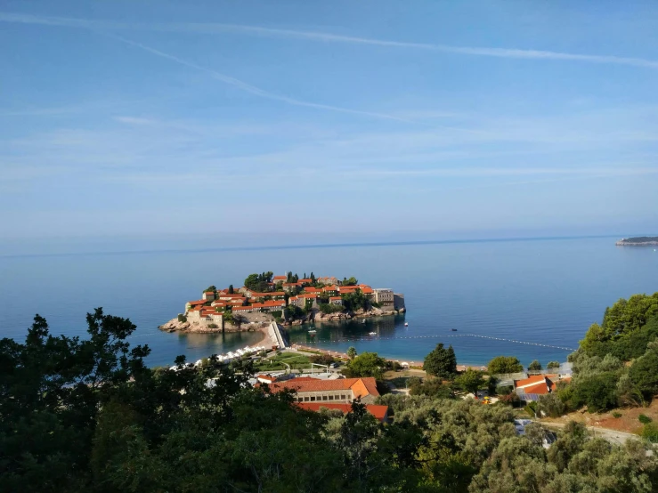 an island with some red roofs surrounded by trees