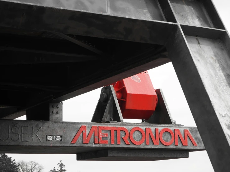 there is a red metronom sign under the bridge