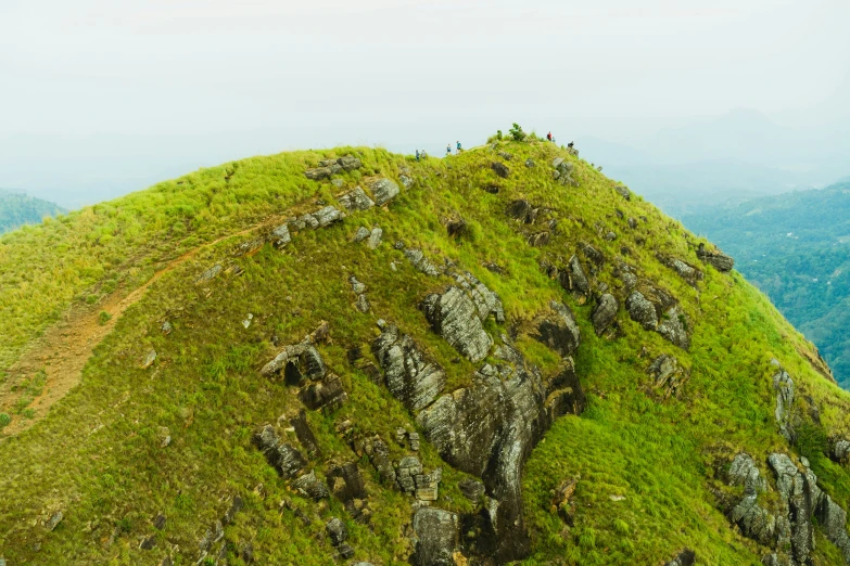 a large grass covered mountain with people standing on top